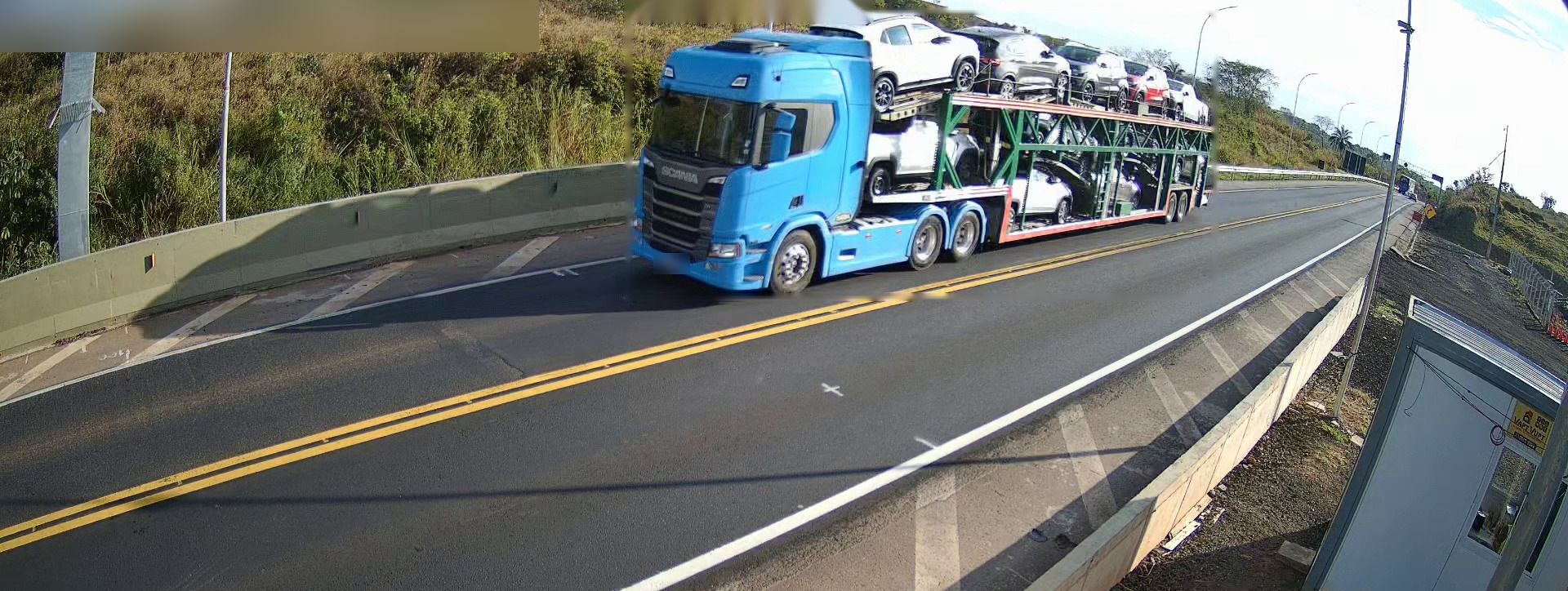 Caminhão-cegonha em rodovia, visto por uma câmera de monitoramento